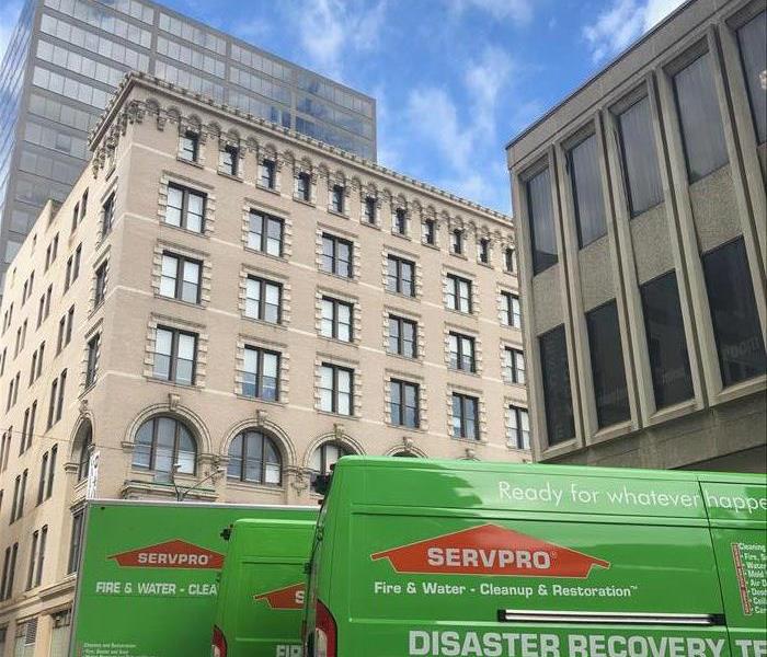 SERVPRO van parked in front of a tall grey building. 